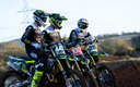 Three dirt bike riders with their Triumph bikes on a track, wearing helmets and racing gear.